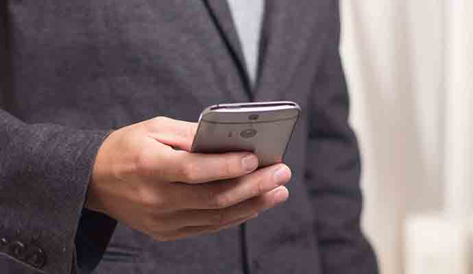 Zögern Sie nicht Kontakt mit uns aufzunehmen Mann im Anzug schaut auf sein Smartphone